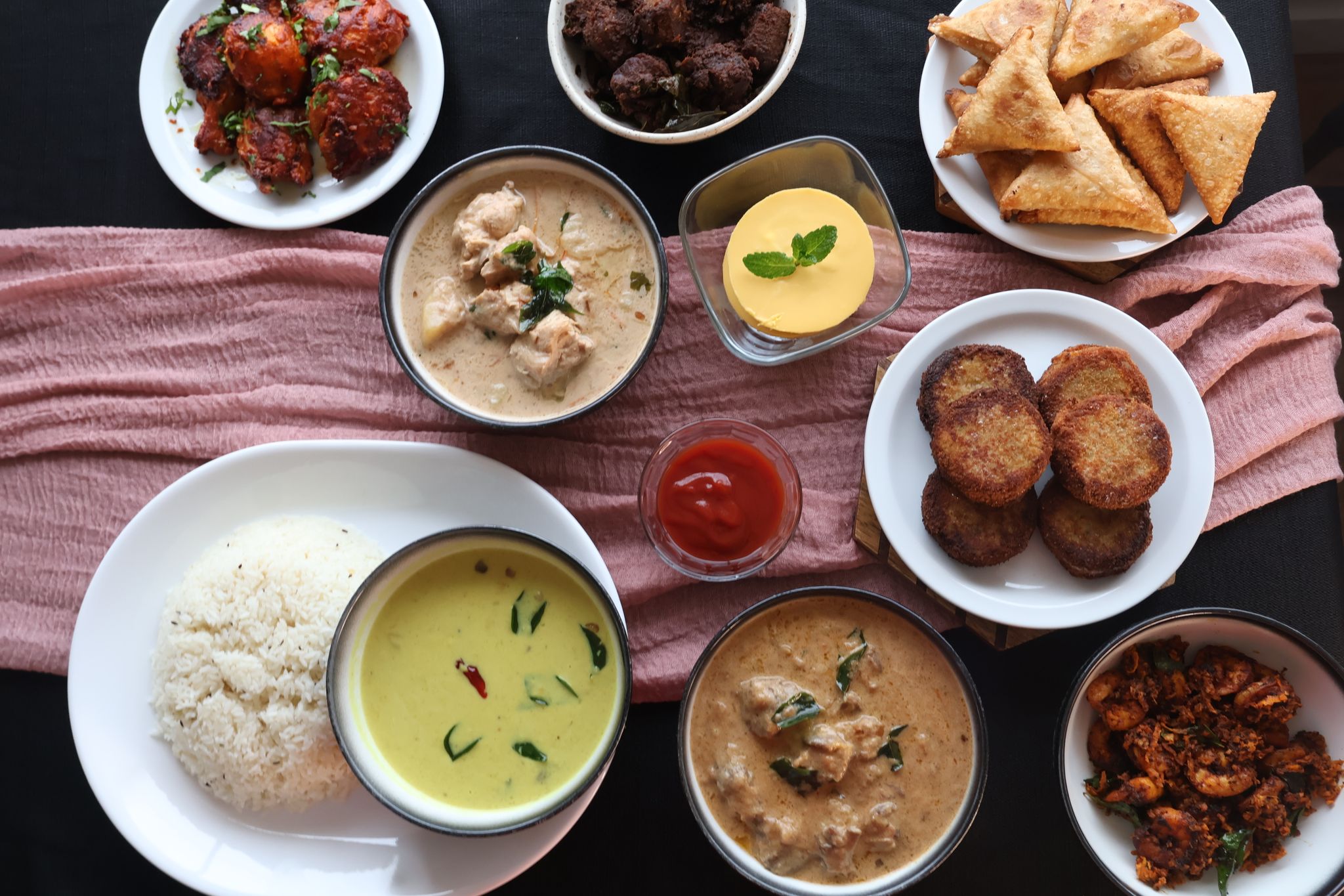 A stunning spread of dishes including curries, samosas, cutlets, and rice
